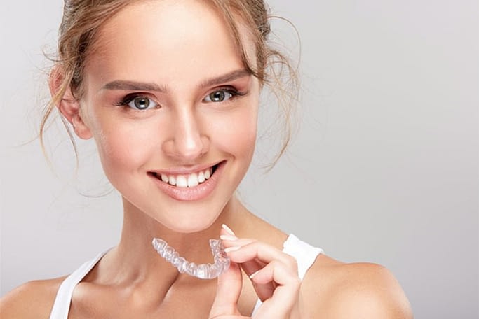 Young women holding her Invisalign retainer and smiling