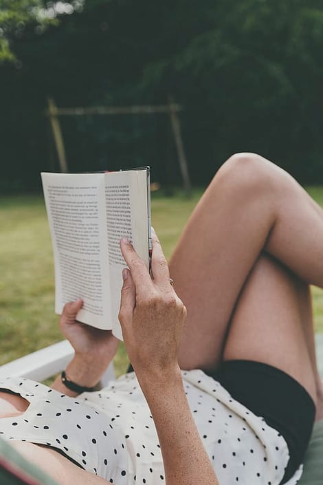 A woman wearing a polka dot top reading a book.