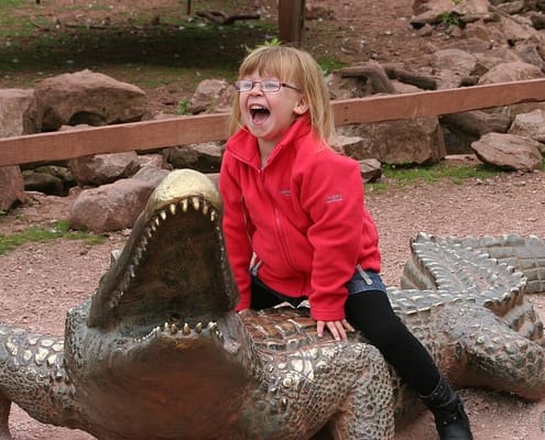 child riding crocodile statue at zoo