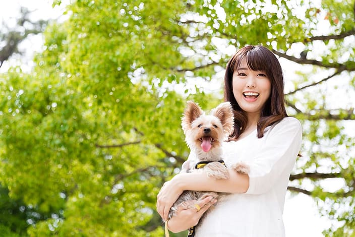 A happy woman holding a small happy dog.